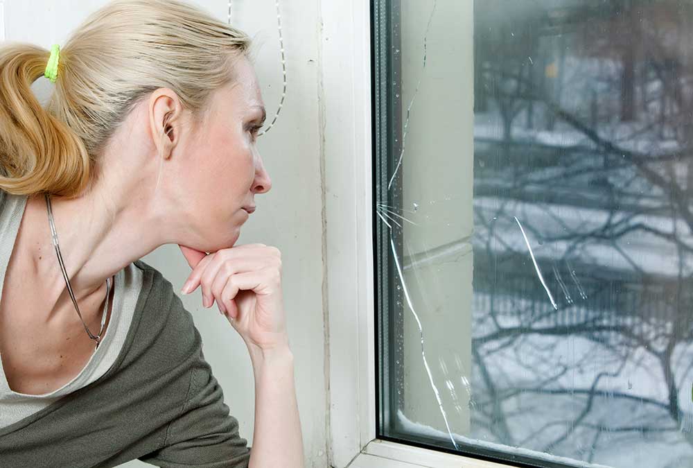 Woman inspecting cracked window